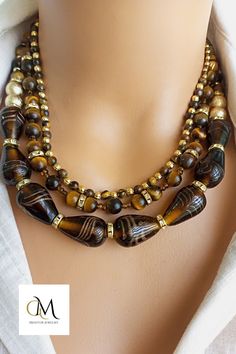 This exquisite piece perfectly combines vibrant Indian glass beads with the earthy allure of Tiger Eye natural stones. Each bead is meticulously handcrafted, showcasing the rich cultural heritage of India. The warm hues of the Tiger Eye stones create a captivating contrast against the intricately designed glass beads, making this necklace a true statement piece. With its adjustable length and secure clasp, it can be easily customized to fit any neckline. Spiritual Brown Necklace With Faceted Beads, Elegant Brown Beaded Necklace With Gemstone Beads, Elegant Brown Gemstone Beaded Necklaces, Elegant Brown Gemstone Beaded Necklace, Brown Beaded Necklaces With Oval Beads, Brown Beaded Necklace With Oval Beads, Brown Faceted Beads Jewelry For Healing, Gold Beaded Necklaces With Natural Stones And Czech Glass, Handmade Brown Glass Jewelry