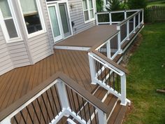 a wooden deck with white railings next to a house