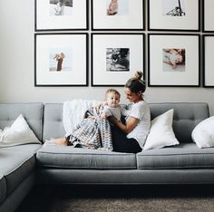 a woman sitting on top of a gray couch next to a child