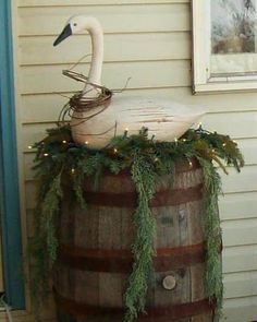 a swan sitting on top of a wooden barrel next to a building with christmas lights