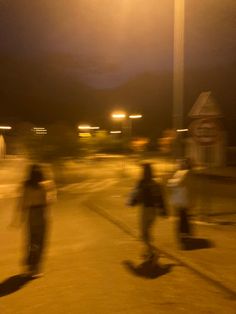 blurry image of people walking down the street at night with traffic lights in the background