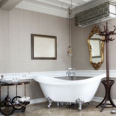 a bath tub sitting under a mirror in a bathroom next to a chandelier