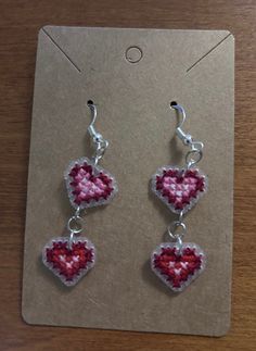 a pair of earrings with hearts hanging from them