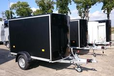 three black trailers are parked in a row