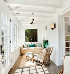 the sun shines through the windows onto an enclosed porch with wicker chairs and couches