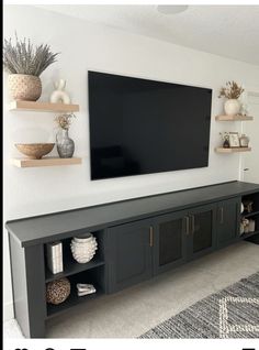 a flat screen tv mounted to the side of a wall in a living room with shelves