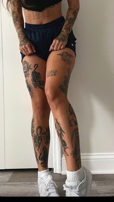 a woman with tattoos on her legs standing next to a door