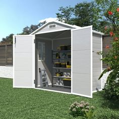 a white shed with its doors open on the grass