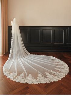 a bride's wedding dress is shown in front of a window, with the veil pulled back