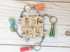 a wooden puzzle piece keychain with tassels attached to it on a table