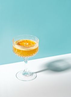 a glass filled with liquid sitting on top of a white table next to a blue wall