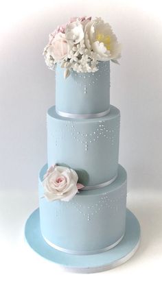 a three tiered blue cake with flowers on top