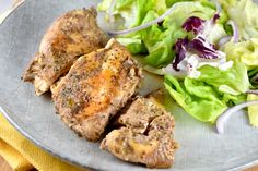 a plate with chicken, lettuce and salad on it next to a yellow napkin