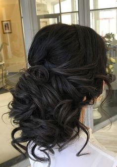 the back of a woman's head with wavy black hair in a low bun