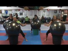 people are doing exercises with large balls on the floor in front of them, while others look on