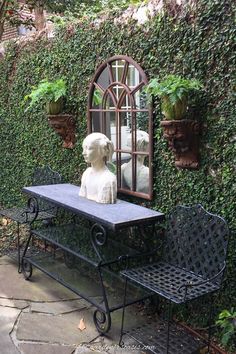 a statue sitting on top of a black bench next to a mirror and potted plants