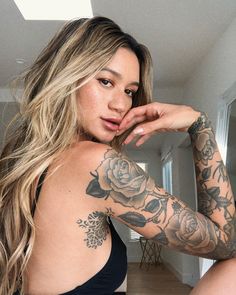 a woman with tattoos on her arm posing for the camera