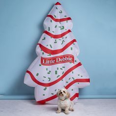 a small white dog sitting next to a large christmas tree shaped inflatable balloon