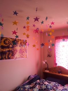 a bedroom with pink walls and colorful stars on the wall hanging above the bedspread