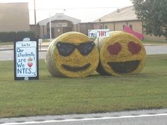 two hay balls that have been placed in the grass with faces drawn on them and one has sunglasses