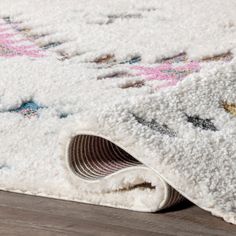 a white rug is laying on the floor next to a wooden floor with an area rug