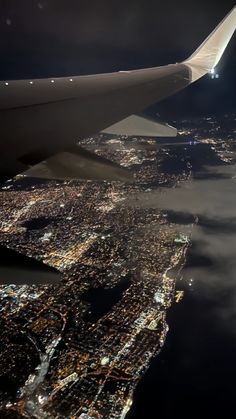 an airplane wing flying over the city lights