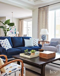 a living room filled with blue couches and pillows on top of a coffee table