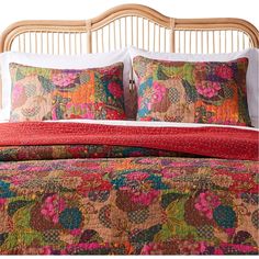 the bed is made up with colorful pillows and blankets on top of it, along with two pillow cases