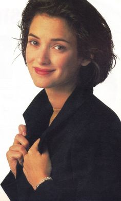 a woman is smiling and posing for the camera with her hands on her chest, wearing a black jacket