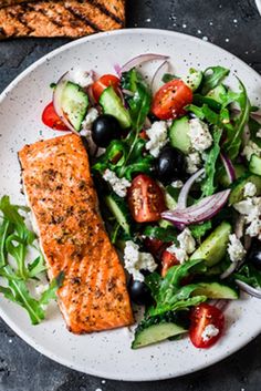 a white plate topped with salad and salmon