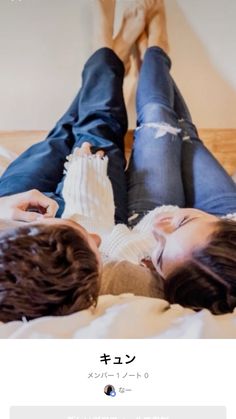 two people laying on top of a bed next to each other with their feet up