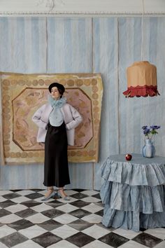 a woman standing in front of a painting on the wall next to a checkered floor