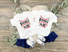 two shirts that say double play and baseball with shoes on the floor next to them