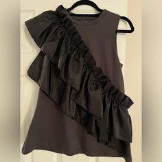 Ruffled Sleeveless Top- Stunning Sleeveless Top (Charcoal Color) With Dramatic Wrap-Around Black Ruffle. Top Is Cotton And Super Soft. Fun Date Night Top To Wear With Jeans And Heels. Size - Small Arm Pit To Arm Pit - 17 Inches Length - 26 Inches Never Worn- Excellent Condition. Black Sleeveless Ruffled Tank Top, Black Ruffled Sleeveless Tank Top, Sleeveless Black Ruffled Tank Top, Black Ruffled Tank Top, Black Ruffled Tank Top For Party, Black Sleeveless Top With Ruffles, Black Sleeveless Ruffled Top, Chic Ruffled Tank Top For Layering, Chic Black Ruffled Tank Top