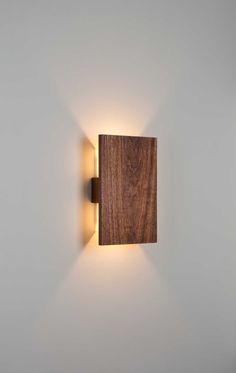 a wooden wall light mounted on the side of a white wall in a room with grey walls