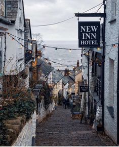 a cobblestone street lined with shops and restaurants next to the ocean in new inn hotel