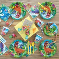 dinosaur party supplies including plates, napkins and utensils on a wooden table