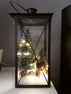 a lighted lantern with a deer and christmas trees in it