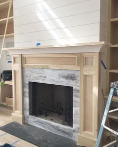 a fireplace being built in a living room with white paint on the mantle and shelves