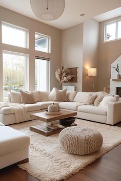 a living room filled with white furniture and large windows on the side of the wall