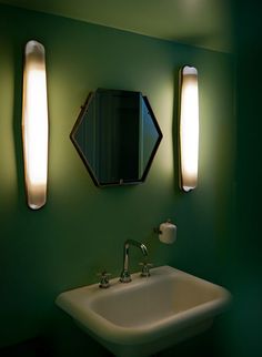 a bathroom sink sitting under two mirrors next to a wall mounted faucet with lights on it