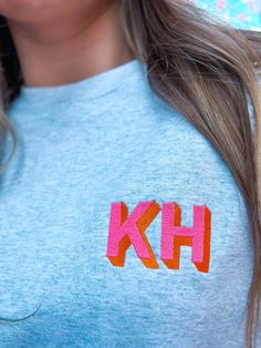 a woman wearing a blue shirt with the letter kh on it's chest