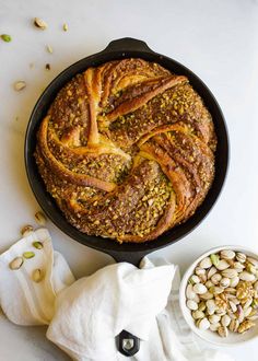 a pan filled with bread and nuts on top of a white table next to napkins