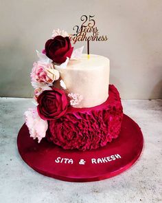 a wedding cake with red flowers on top