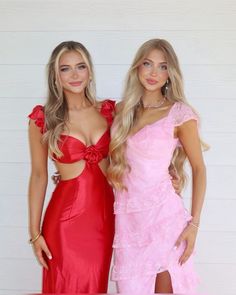 two beautiful young women standing next to each other in red dresses and one is wearing a pink dress