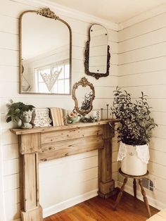 a wooden table sitting next to a mirror and potted plant on top of it