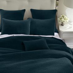 a bed with dark green bedspread and pillows