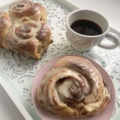 two pastries are sitting on a tray next to a coffee cup and saucer