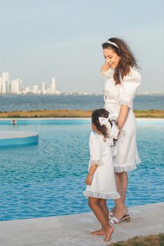 a mother and daughter standing in front of a swimming pool