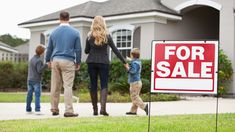 a family walking in front of their house with a for sale sign on the lawn